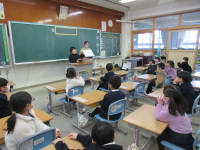 教卓の前で、全員に向かってクイズを出す本校児童と教員