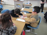 アイマスクをして点図を触るみどり小学校の児童と、ヒントを出すみどり小学校の児童