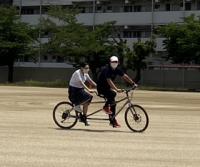 タンデム自転車に教員と乗っている生徒