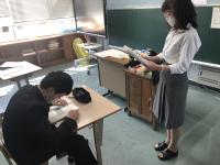 机に向かう男子生徒と説明する教員 机に向かう男子生徒と説明する教員