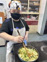 材料をフライパンで炒める児童