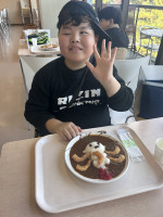 児童がラッコの形をしたご飯の乗っているカレーを食べている。