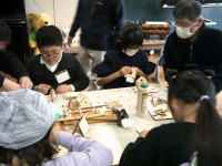 参加者４名が一つの机で一緒に小物入れを作っている。